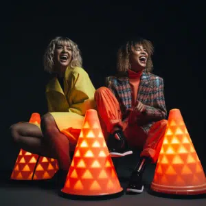 neon female models sitting on cones looking happy and surprised